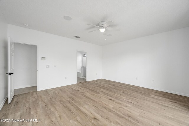 empty room with light wood finished floors, ceiling fan, visible vents, and baseboards