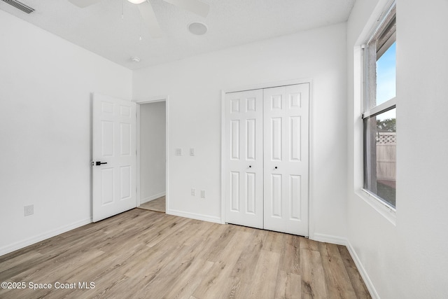 unfurnished bedroom featuring baseboards, visible vents, a ceiling fan, wood finished floors, and a closet