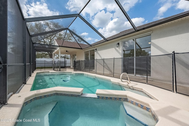 view of pool featuring a pool with connected hot tub, a patio area, fence, and a lanai