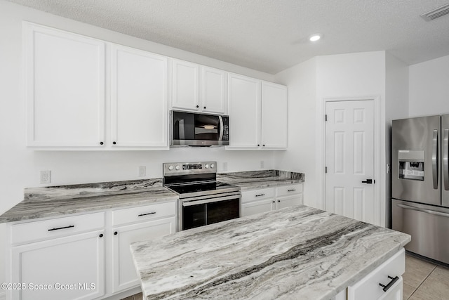 kitchen featuring appliances with stainless steel finishes, white cabinets, visible vents, and light stone counters