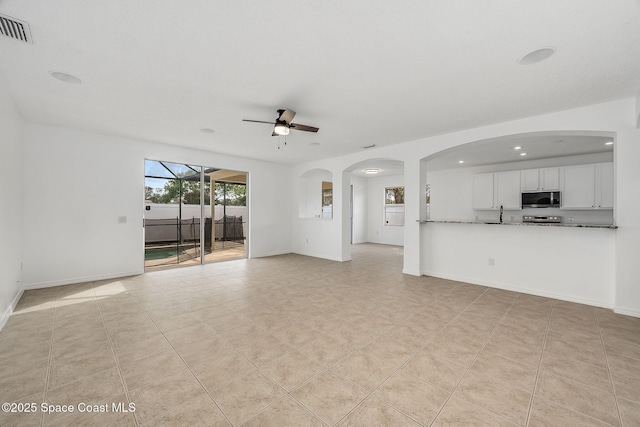 unfurnished living room featuring light tile patterned flooring, a sink, visible vents, baseboards, and a ceiling fan