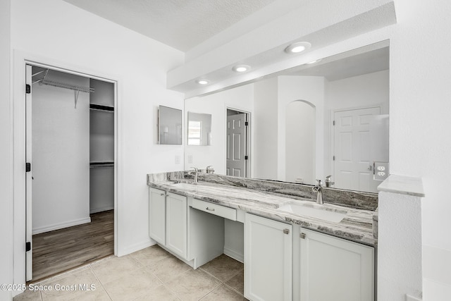 full bathroom featuring tile patterned floors, a sink, a spacious closet, and double vanity