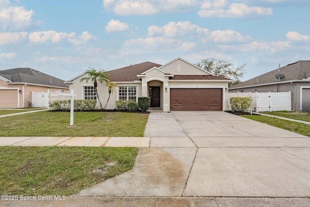 view of front of house with concrete driveway, a gate, fence, a front lawn, and stucco siding