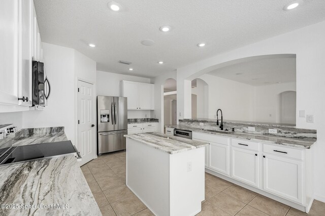 kitchen with black microwave, a kitchen island, a sink, stainless steel fridge with ice dispenser, and electric range oven