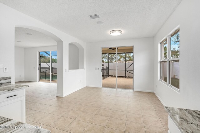 empty room featuring a healthy amount of sunlight, visible vents, baseboards, and light tile patterned floors