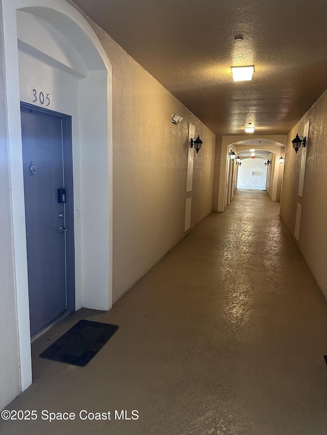 corridor with concrete flooring and a textured ceiling