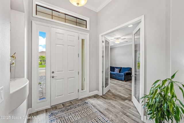 entryway with baseboards, ornamental molding, and wood finished floors