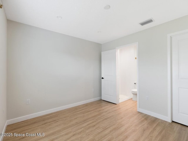 unfurnished bedroom with ensuite bathroom and light hardwood / wood-style floors