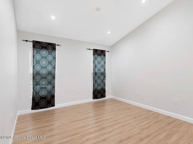 spare room with lofted ceiling and light hardwood / wood-style flooring