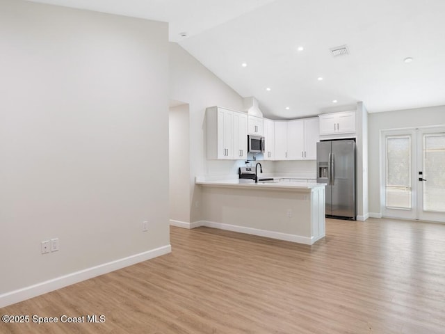 kitchen with sink, light hardwood / wood-style flooring, kitchen peninsula, stainless steel appliances, and white cabinets