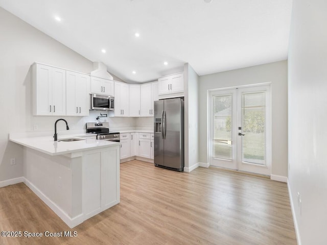 kitchen featuring lofted ceiling, sink, appliances with stainless steel finishes, kitchen peninsula, and white cabinets