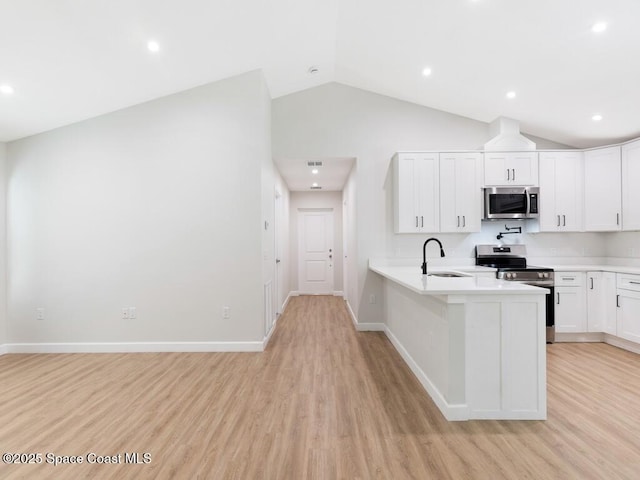 kitchen featuring sink, white cabinetry, vaulted ceiling, light hardwood / wood-style flooring, and stainless steel appliances