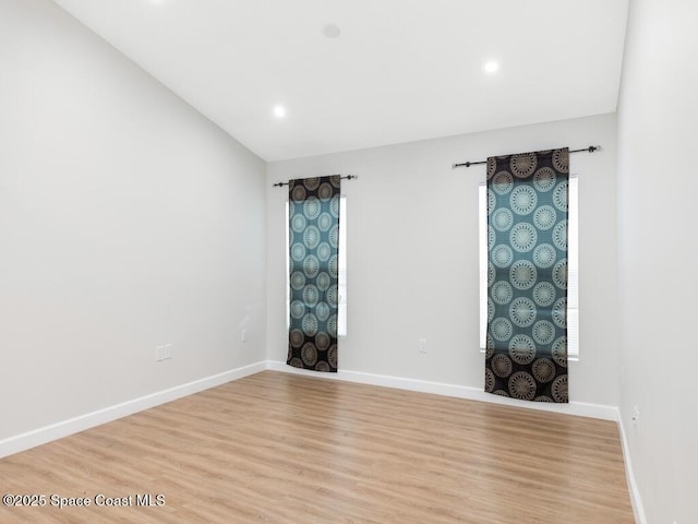 spare room with vaulted ceiling and light hardwood / wood-style floors