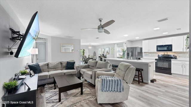 living room with sink, light hardwood / wood-style floors, a textured ceiling, and ceiling fan