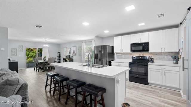 kitchen with black appliances, white cabinets, and a kitchen bar