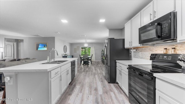 kitchen featuring white cabinetry, sink, a kitchen island with sink, and black appliances