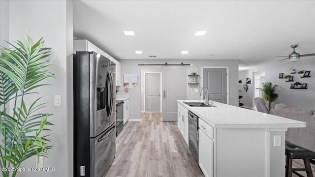 kitchen with sink, stainless steel fridge, white cabinets, black range with electric cooktop, and a barn door