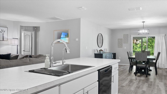 kitchen featuring decorative light fixtures, white cabinetry, dishwasher, sink, and light hardwood / wood-style floors