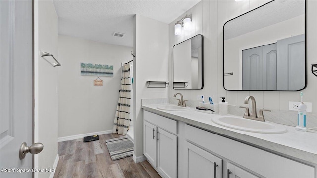 bathroom with vanity, curtained shower, wood-type flooring, and a textured ceiling