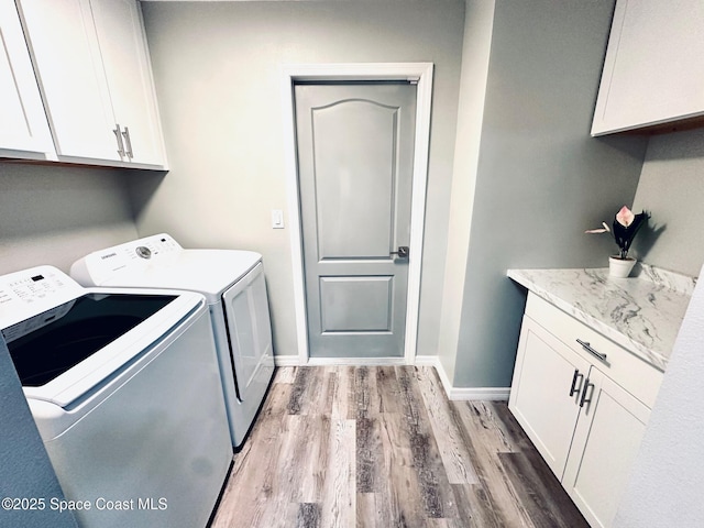 laundry room featuring cabinets, washer and clothes dryer, and light hardwood / wood-style flooring