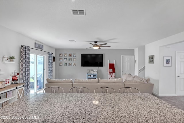 kitchen with ceiling fan, a kitchen bar, and light stone countertops