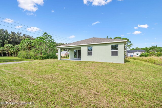 back of property with a yard and stucco siding