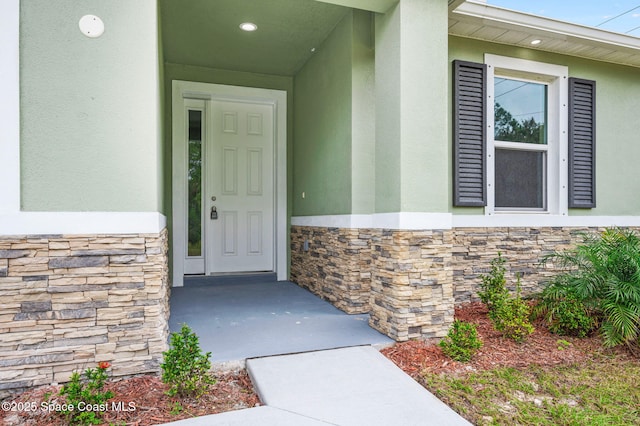 doorway to property featuring stone siding and stucco siding