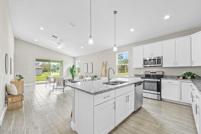 kitchen featuring white cabinets, a center island with sink, stainless steel appliances, and a sink