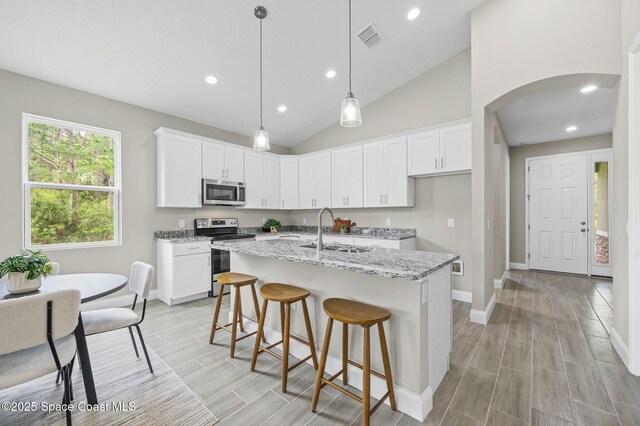 kitchen with stainless steel appliances, white cabinetry, a sink, and light stone counters