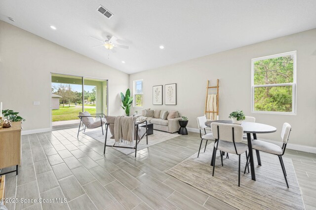 living room with vaulted ceiling, a wealth of natural light, visible vents, and baseboards