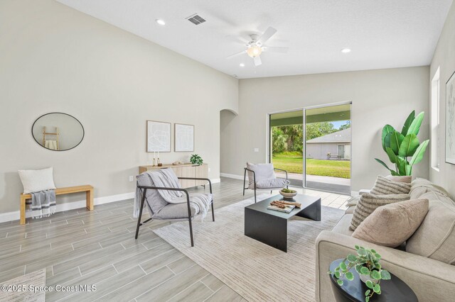 living area featuring visible vents, arched walkways, baseboards, lofted ceiling, and wood tiled floor