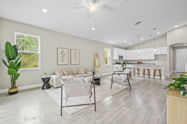 living room with arched walkways, wood finish floors, visible vents, baseboards, and vaulted ceiling