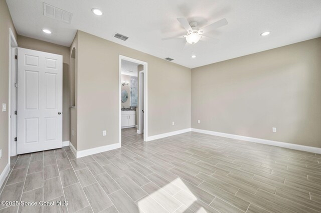 unfurnished bedroom featuring baseboards, visible vents, arched walkways, and recessed lighting