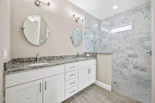 bathroom featuring double vanity, walk in shower, a sink, and recessed lighting