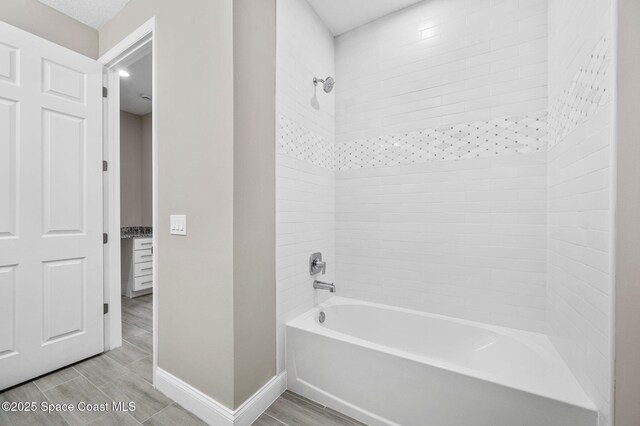 full bath featuring wood tiled floor, bathtub / shower combination, and baseboards