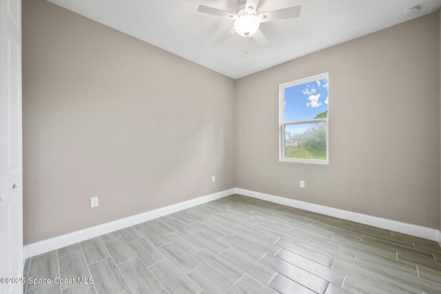 spare room with wood finish floors, a ceiling fan, and baseboards