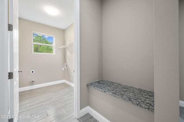 laundry area featuring wood tiled floor, electric dryer hookup, a textured ceiling, laundry area, and baseboards