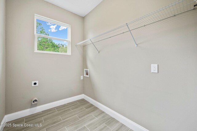 clothes washing area with hookup for a washing machine, wood tiled floor, hookup for an electric dryer, laundry area, and baseboards