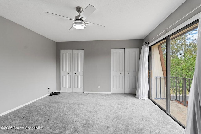 unfurnished bedroom featuring two closets, carpet floors, multiple windows, and access to outside