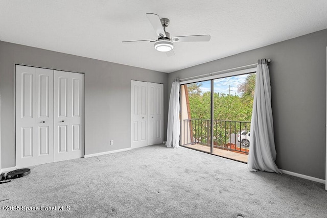 unfurnished bedroom with two closets, carpet floors, access to outside, and ceiling fan