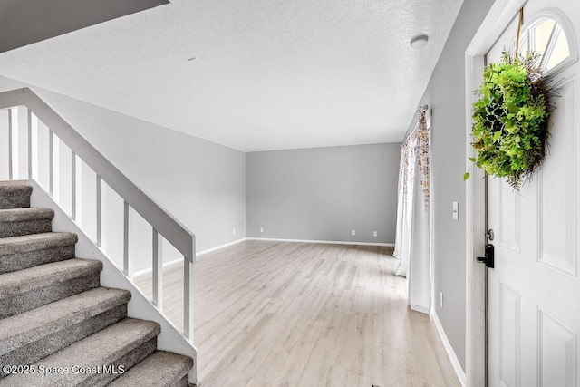 foyer with a textured ceiling and light hardwood / wood-style flooring