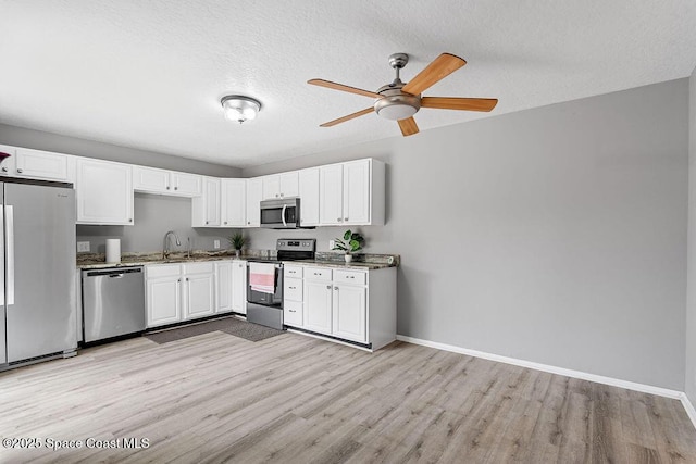 kitchen with white cabinetry, sink, light hardwood / wood-style flooring, and appliances with stainless steel finishes