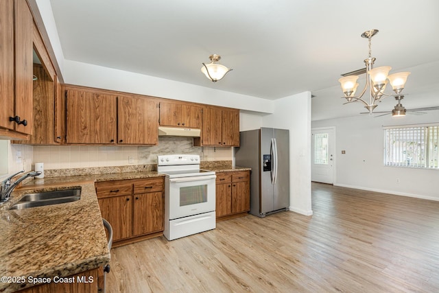 kitchen featuring decorative light fixtures, white electric stove, stainless steel refrigerator with ice dispenser, a sink, and under cabinet range hood