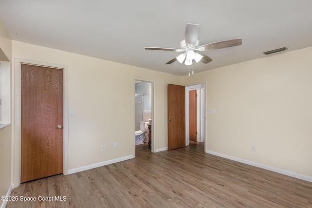 unfurnished bedroom featuring visible vents, ensuite bathroom, light wood-style floors, a ceiling fan, and baseboards