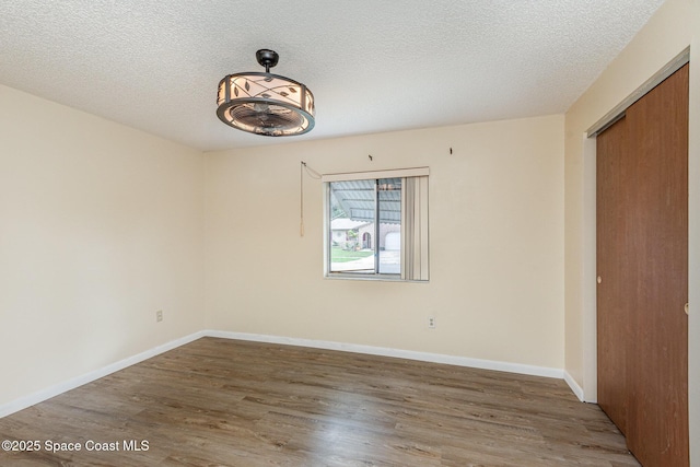 spare room with baseboards, dark wood finished floors, and a textured ceiling