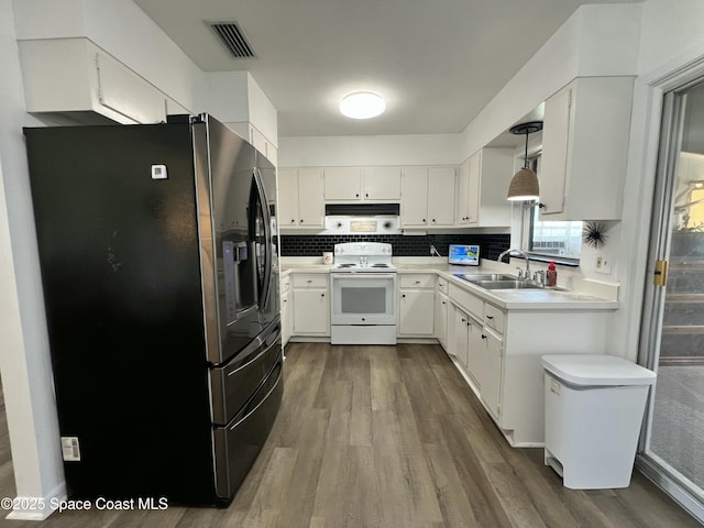 kitchen with sink, white cabinetry, hanging light fixtures, white electric range oven, and stainless steel fridge with ice dispenser