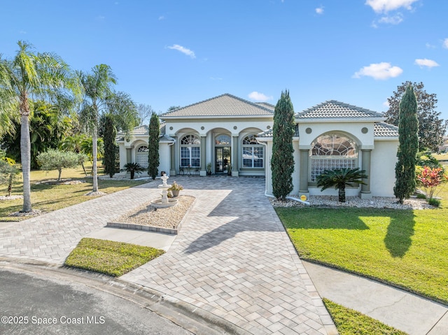 view of front of house featuring stucco siding, a front lawn, decorative driveway, and a tiled roof