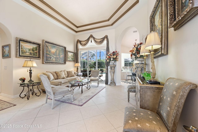 living area featuring light tile patterned floors, baseboards, arched walkways, ornamental molding, and a tray ceiling