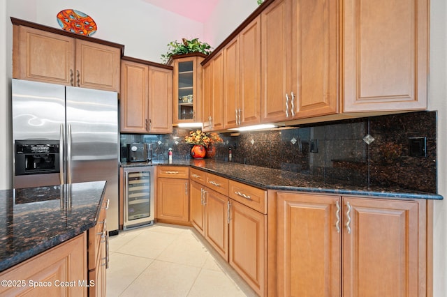 kitchen featuring wine cooler, stainless steel refrigerator with ice dispenser, backsplash, light tile patterned flooring, and dark stone countertops