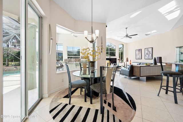 dining area featuring vaulted ceiling, ceiling fan with notable chandelier, light tile patterned flooring, and baseboards